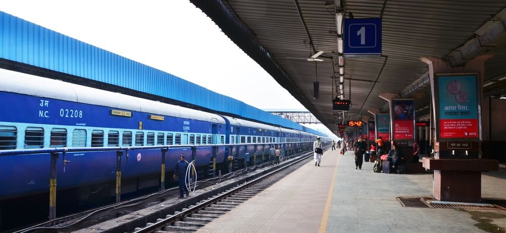 A traveler checking a map train route on a smartphone at a busy railway station platform