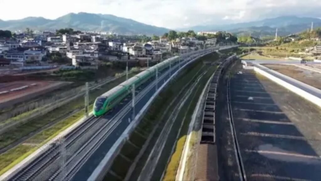 Modern electric transport train traveling on scenic railway tracks.
