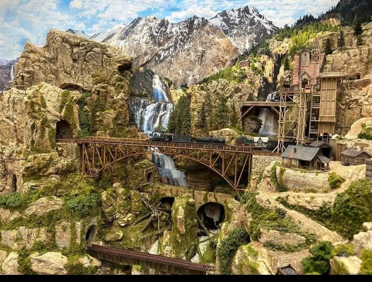 Scenic passenger train crossing a bridge near mountains in the United States.