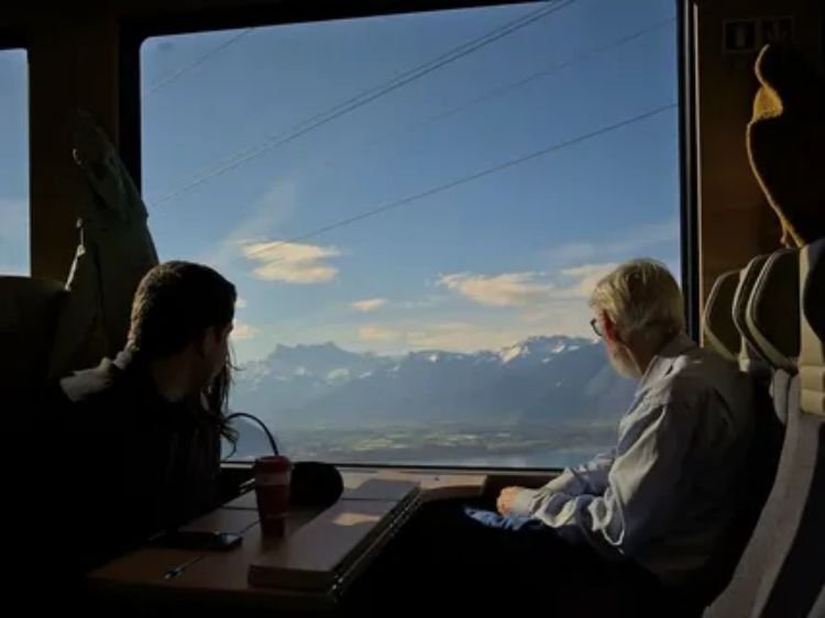 Traveler viewing scenic American landscapes through a train window.