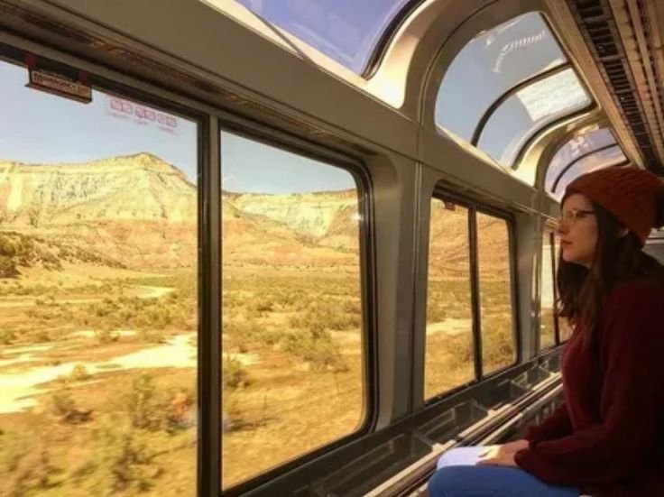 A traveler looking out a train window enjoying peaceful countryside and river views