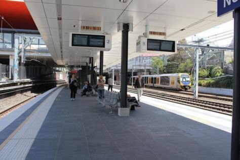 A passenger with a travel bag checking train route details on a smartphone at a station platform