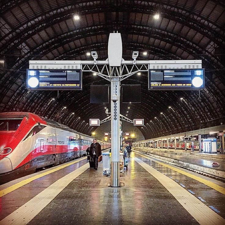 Modern high-speed train parked at a busy Italian railway station platform