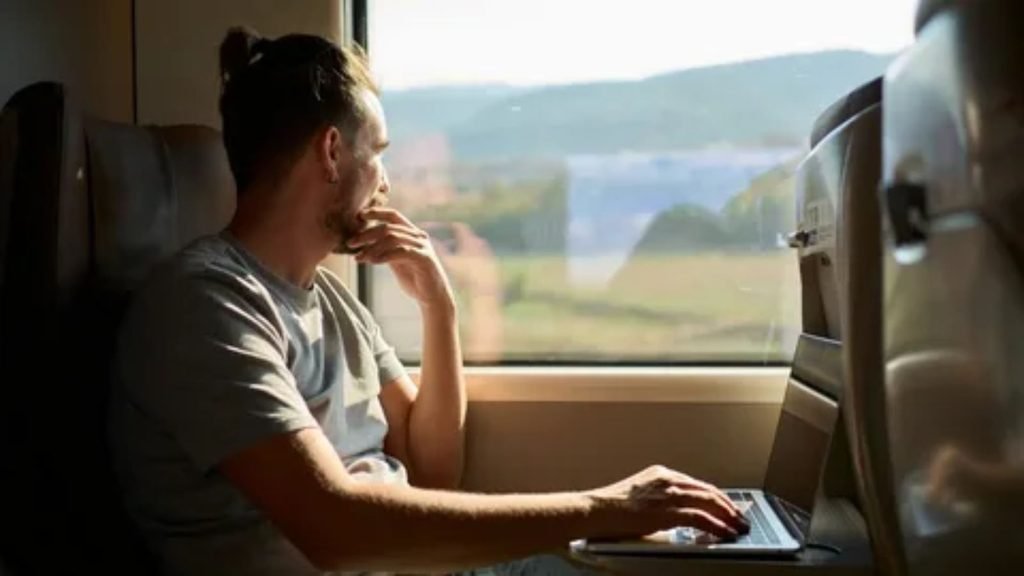 Passenger relaxing inside a sleeper train compartment while enjoying the view