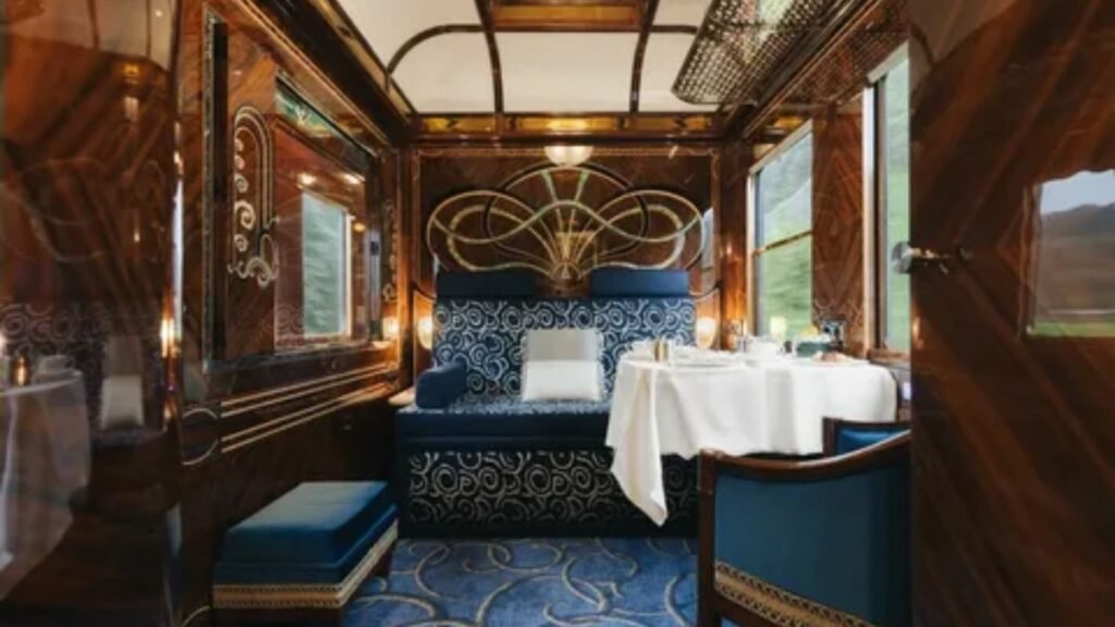 A luxury passenger train traveling through a scenic mountain valley landscape.