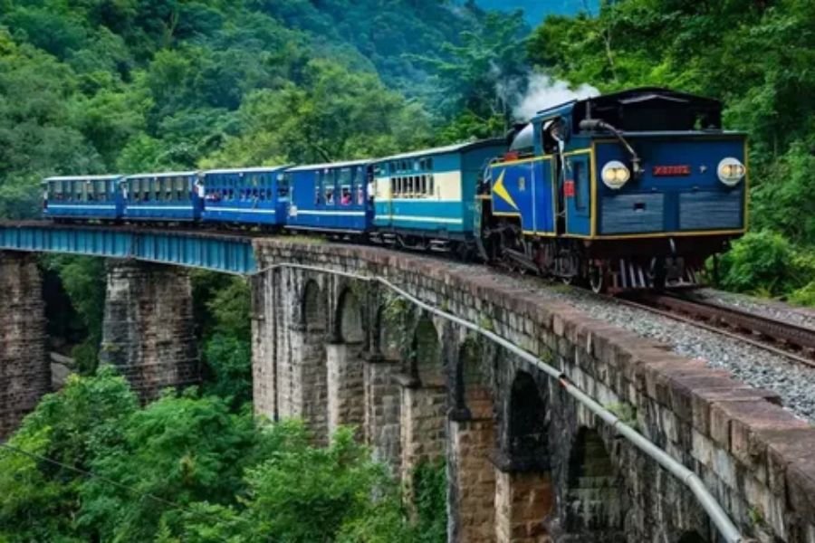 Scenic passenger train traveling through a lush mountain landscape on a railroad vacation.