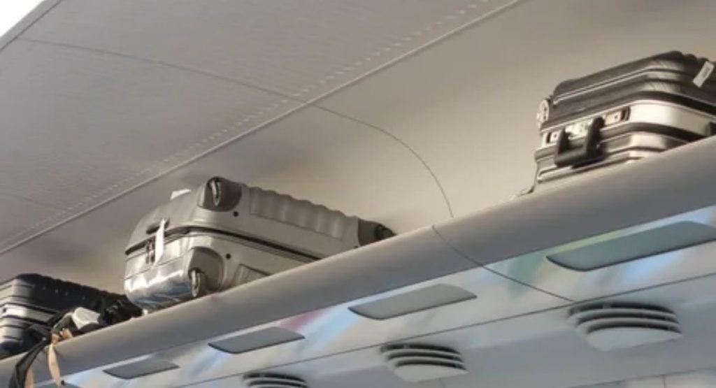 Passenger storing suitcase safely in the train luggage compartment