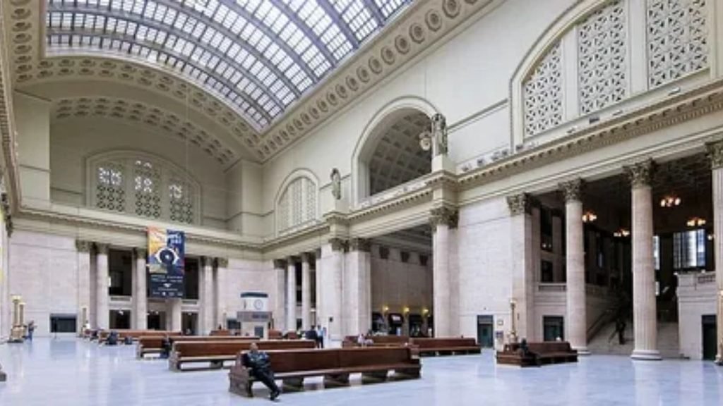 Exterior entrance of a historic downtown Amtrak train station with passengers walking.