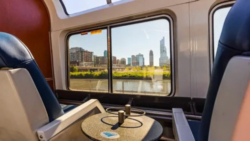 Inside the Amtrak Sightseer Lounge car showing large curved windows and passenger seating