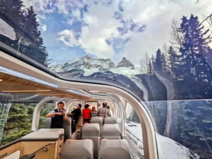 Passenger relaxing inside a glass dome train looking out at mountain scenery in Western Canada