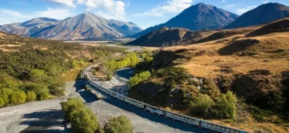 TranzAlpine train crossing scenic river valley and Southern Alps in New Zealand