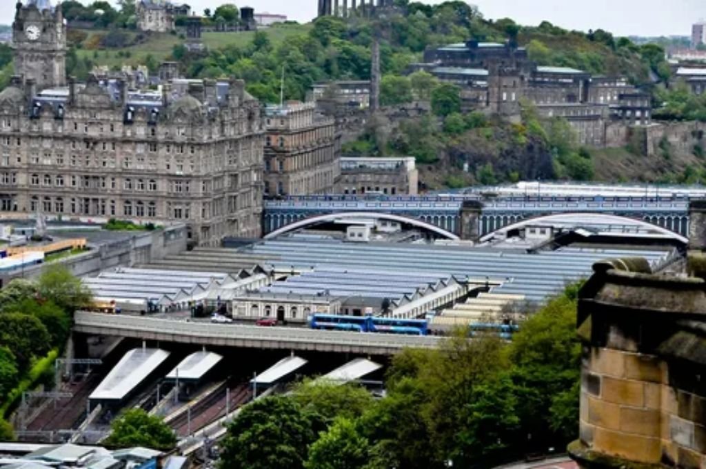 Scenic train journey view approaching Edinburgh Waverley station with Edinburgh landmark backdrop