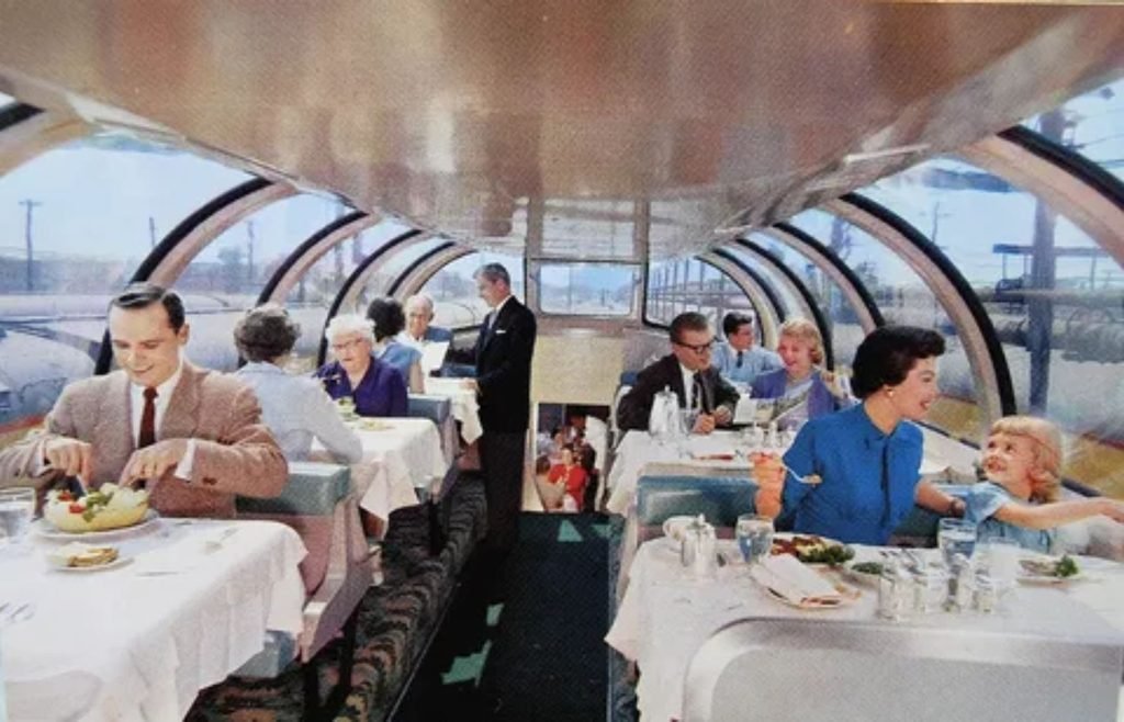 Passengers enjoying dining and scenic views inside the glass dome car of a Canadian train
