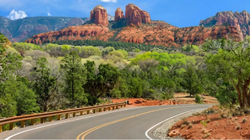 Scenic passenger train traveling through Arizona desert landscape with red rock mountains in the background