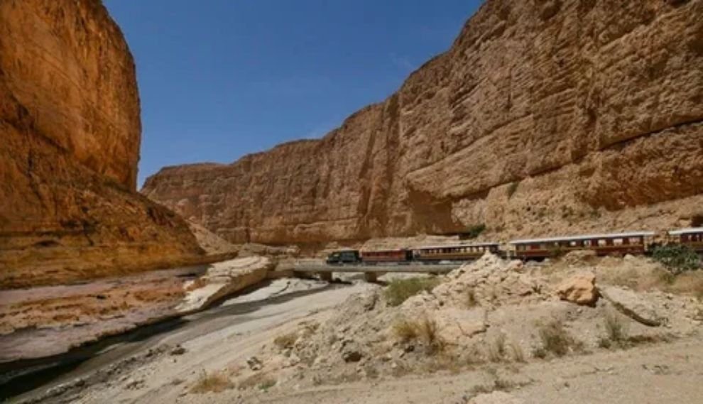 View from a train window showing scenic Arizona red rock formations and desert vegetation